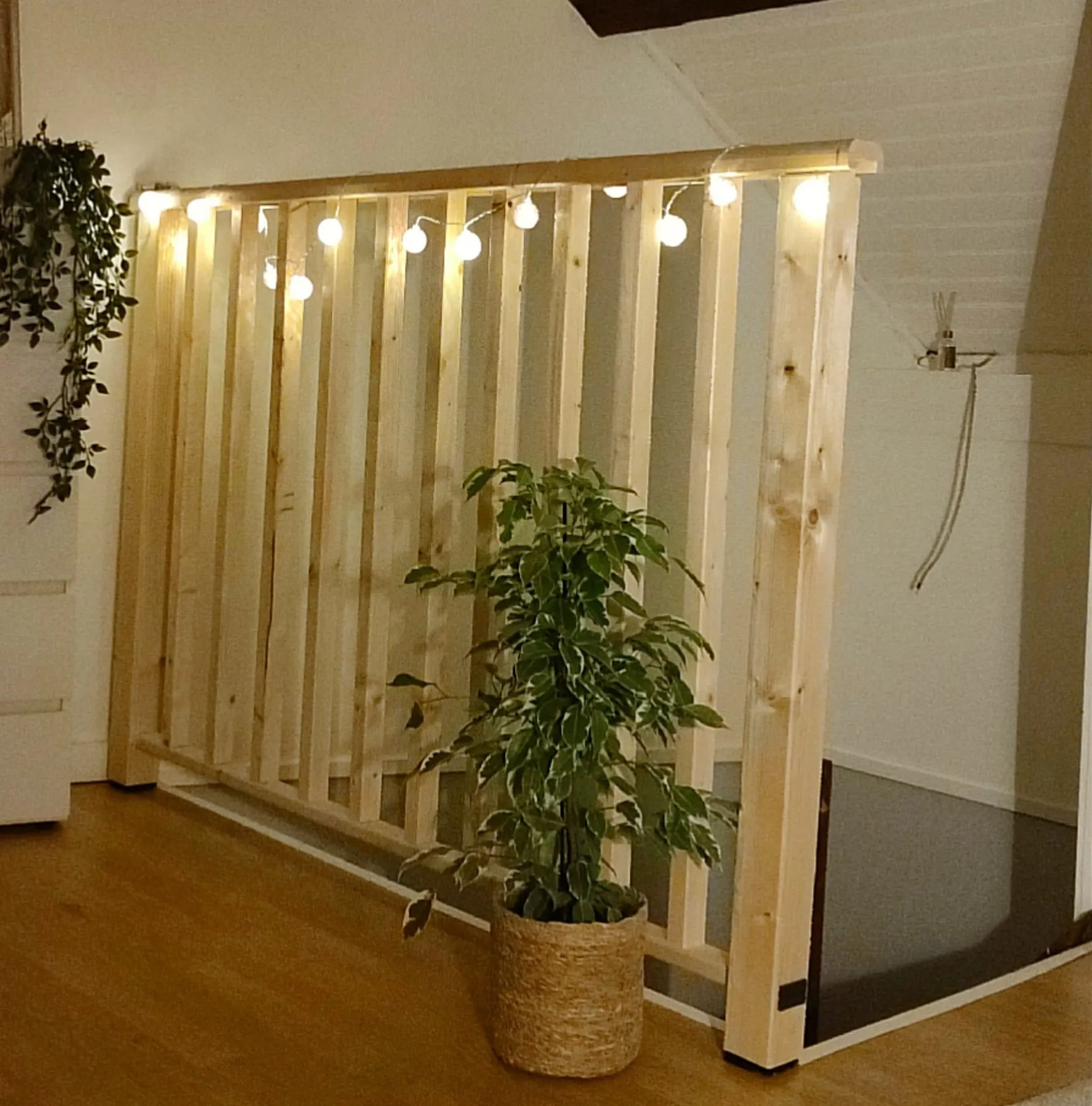 Balustrade en bois clair autour d'une trémie, décorée d'une guirlande lumineuse