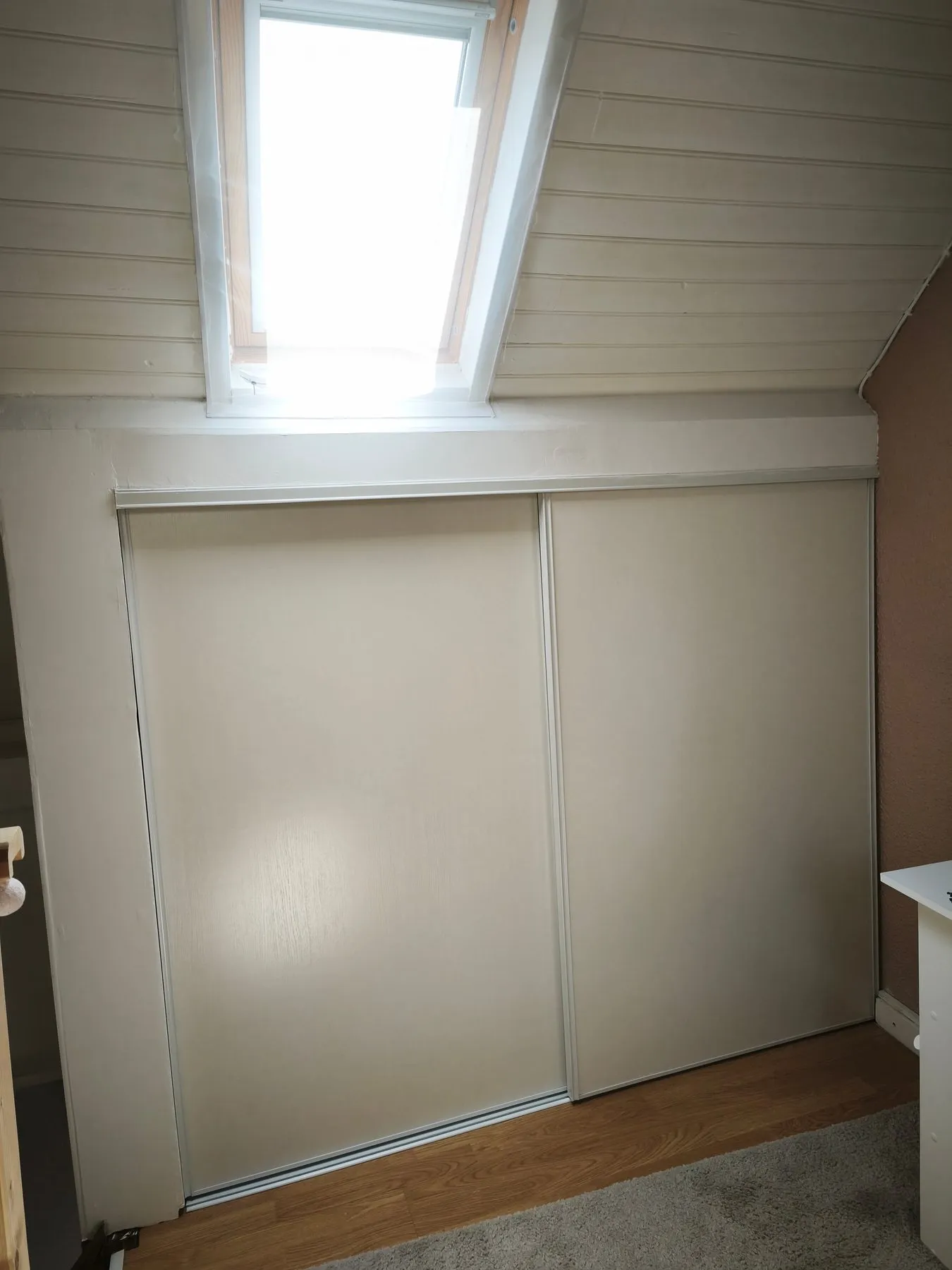 Placard sous pente terminé, avec portes coulissantes claires sous un Velux